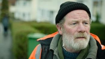 Hector: An older bearded White man in an orange coat and black woolly hat