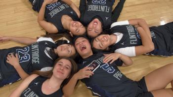 Home Court movie: Six teen girls in uniform jerseys lie on their backs in a circle surrounding Ashley Chea