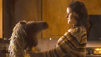 Horsegirls movie: Margarita (Lilian Carrier) looks at a hobby horse while standing in a kitchen