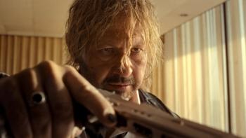 Hot Spot movie: A man with long hair points a gun indoors