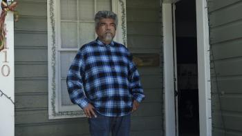 How the Gringo Stole Christmas Movie: Bennie (George Lopez) stands on his front porch, which is decorated for Christmas, looking grumpy