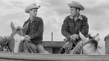 Hud: Brandon de Wilde and Paul Newman look at each other as they sit astride horses