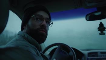 Hunting Matthew Nichols Movie: Markian is in the driver's seat of his car, head turned around to look at the rear