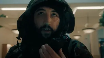 iHostage movie: Dutch Moroccan man in hoodie center holds phone in front of himself and speaks into it while standing inside an Apple store