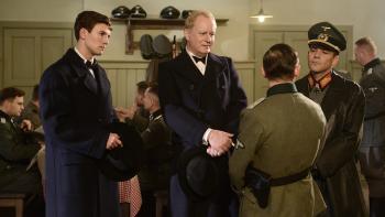 I'll Find You Movie: Leo Suter and Stellan Skargard look concerned while speaking with Nazi officers in a dining hall