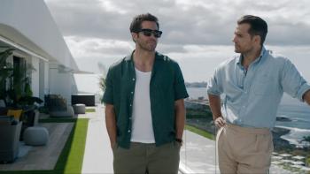 In the Grey movie: Jake Gyllenhaal and Henry Cavill walk on a sunlit patio by the sea, dressed casually, with clouds overhead