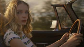 Influencers movie: White French woman with blond hair in striped grey and white shirt, left, drives a convertible with the roof down