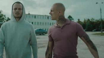 Inside Furioza movie: White Polish man in white hoodie left walks outside with White Polish bald man with many tattoos in pink shirt right