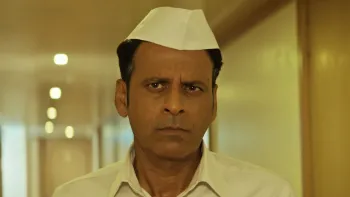 Inspector Zende movie: Indian man with short black hair in white shirt and white hat walks down hallway