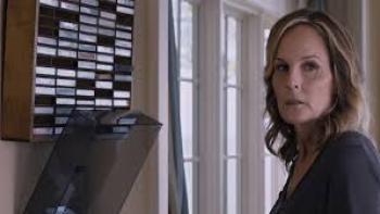 I See You:  a woman looks worried as she stands near a window