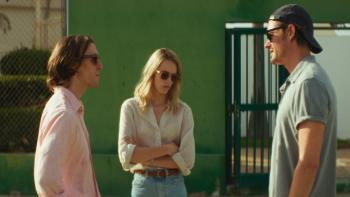 Islands: Two White men and one White woman wearing sunglasses talking outdoors in a sunny setting