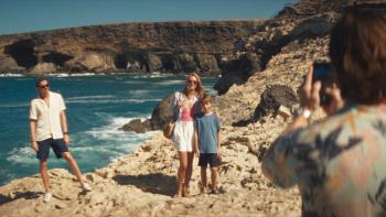 Islands: A father takes a photo of his wife and their son on the beach as another man stands off to the side