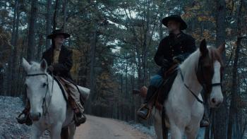 The Isolate Thief Movie: Ada and "Fiddler" John ride side-by-side through the woods; Ada looks at John as he speaks