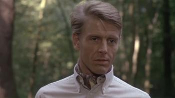 The Day of the Jackal: Edward Fox stands in a forest wearing a light-coloured shirt
