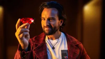 Jewel Thief: The Heist Begins movie: Indian bearded man in white t-shirt and red overcoat center holds up large red diamond