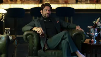 Jewel Thief: The Heist Begins movie: Indian bearded man in nice black suit and silver necklace sits in luxurious black leather chair holding drink