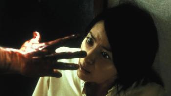 Ju-On—The Grudge: A frightened woman looks at a bloodied hand reaching toward her
