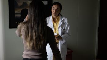 Junction Movie: Mary (Ashley Madekwe), wearing a white lab coat, listens to a patient whose back is to viewers