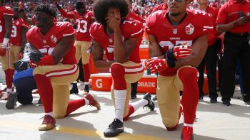 Colin Kaepernick (center) and San Francisco 49ers teammates taking a knee during the U.S. national anthem.