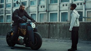 The Kitchen: A Black man rides in on a motorbike toward a young Black teenage boy.