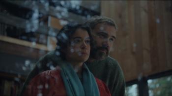 Keeper Movie: Liz and Malcolm look out the window of the cabin, the woods reflecting against the glass