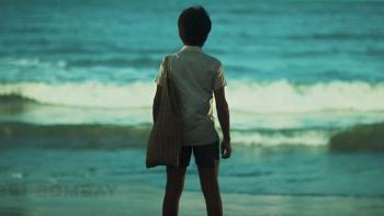 K.G.F -- Chapter 1: A young boy has his back to camera while looking out at the waves crashing in the sea