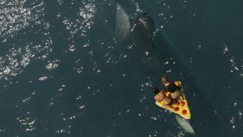 Killer Whale Movie: An overhead view shows the two women on the yellow float, a huge whale swimming beneath them