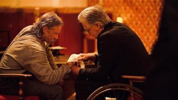 Killing Faith Movie: Bender sits opposite Preacher Ross, as the latter bandages the former's wounded hand