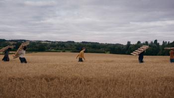 Kindling: Figures carry wood across a field.