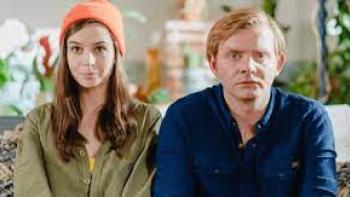 Kiss, Kiss! Movie: A White man and woman sit on a sofa
