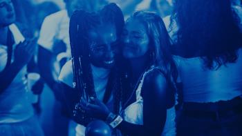 How to Have Sex: Two teenage girls, one Black and one White, dance together in a club with blue lighting.