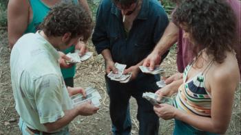 La Chimera: A group of people stand in a circle exchanging notes of money