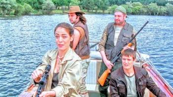 Lake Placid 3: Four people on a boat with rifles, on a lake surrounded by trees.
