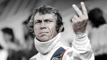 Le Mans: Steve McQueen in racing suit making the V-sign with fingers