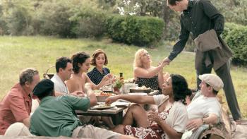 Lee movie: Lee (Kate Winslet) shakes Roland's (Alexander Saarsgard) hand while seated at a garden party