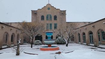 Letters at Christmas: The courtyard entrance to an historic Southwest-style building with a fountain, bare trees, and covered in a layer of snow.