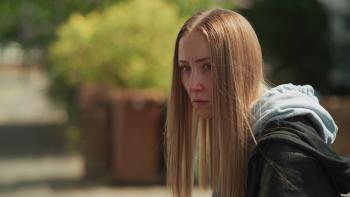 Reawakening: A young woman with long hair looks serious while in the street