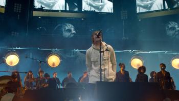 Liam Gallagher: Knebworth 22 -- White middle-aged rock singer in white coat performs on stage with big screens behind