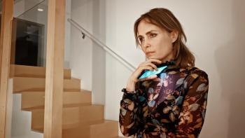 Life Upside Down Movie: Radha Mitchell looks sadly out her window, holding her phone just below her chin