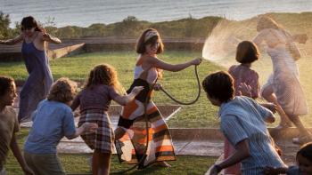 L’immensità: Penelope Cruz sprays water from a hose, surrounded by children on a lawn