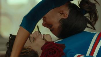 L’immensità: Luana Giuliani lies on her back with a rose in her mouth as Penélope Nieto Conti bends backwards on top of her, their faces close together