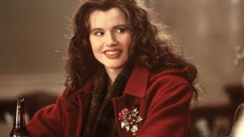 The Long Kiss Goodnight: Geena Davis wears a red coat and smiles, a drink bottle in front of her