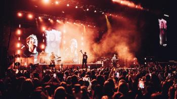 Louis Tomlinson -- All of Those Voices: Louis Tomlinson stands on a stage with his band singling to a large crowd