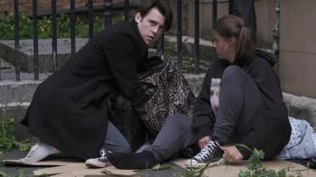Love Without Walls: Niall McNamee crouches over, looking inside a bag, while Shana Swash sits next to him against a wall