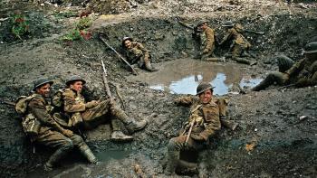 Oh! What a Lovely War: A group of soldiers with rifles lay low in a muddy trench