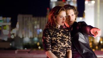 Eric Bana and Drew Barrymore stand on a rooftop in fancy clothing. Eric is directing Drew to look where he is pointing.