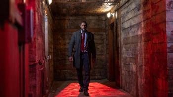 Luther - The Fallen Sun: Idris Elba as John Luther walks toward camera in a red-lit corridor