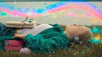 Magnetosphere: Maggie lies with eyes closed in the grass wearing headphones below a rainbow swirl in the sky and colorful dots all around.