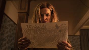 Marionette: Dr. Marianne Winter holds a piece of paper up in front of her, looking concerned.