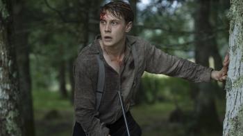 Marrowbone: Young man with a cut on his forehead holding a gun, looking anxious in a forest setting